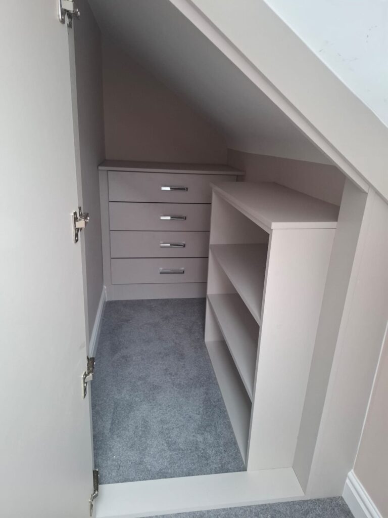 Custom under eaves storage in a loft conversion with drawers and shelving.