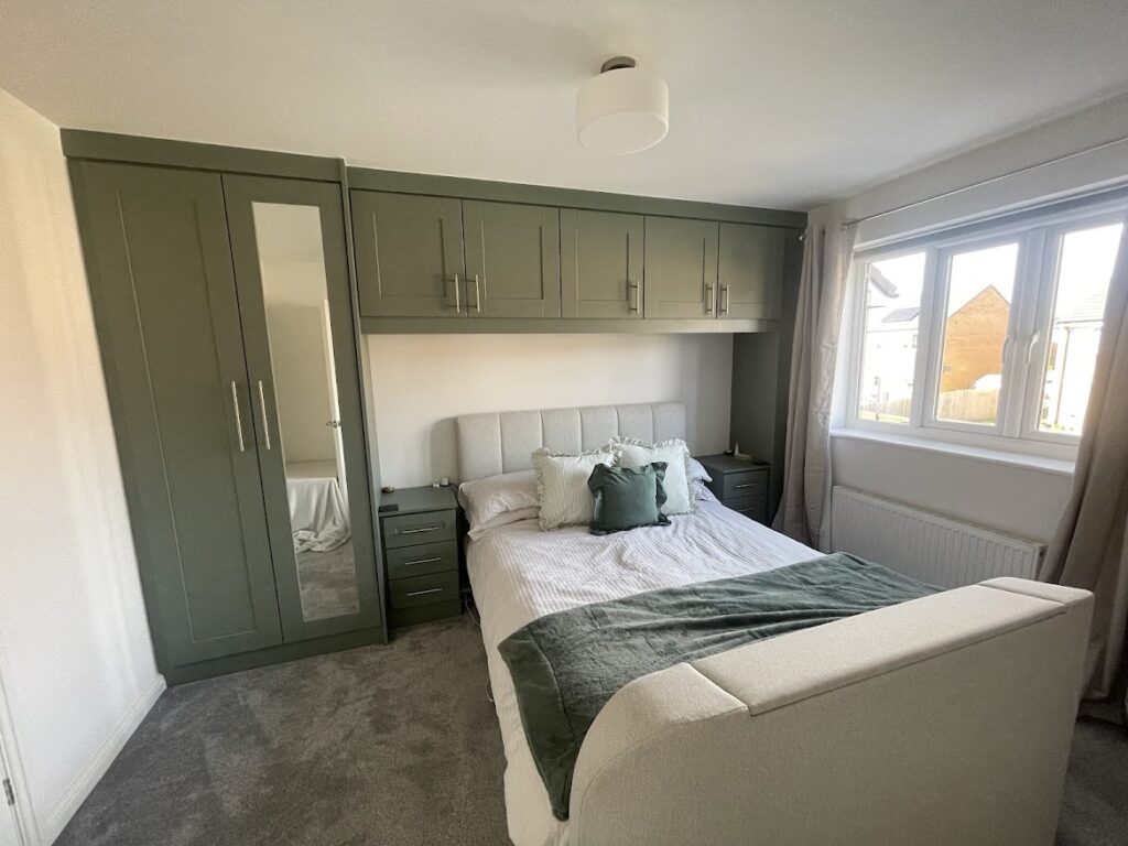 Over bed green cabinets and matching wardrobe with mirror panel