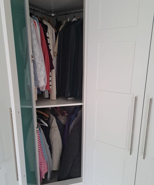 Corner wardrobe interior with curved hanging rail maximising storage space.