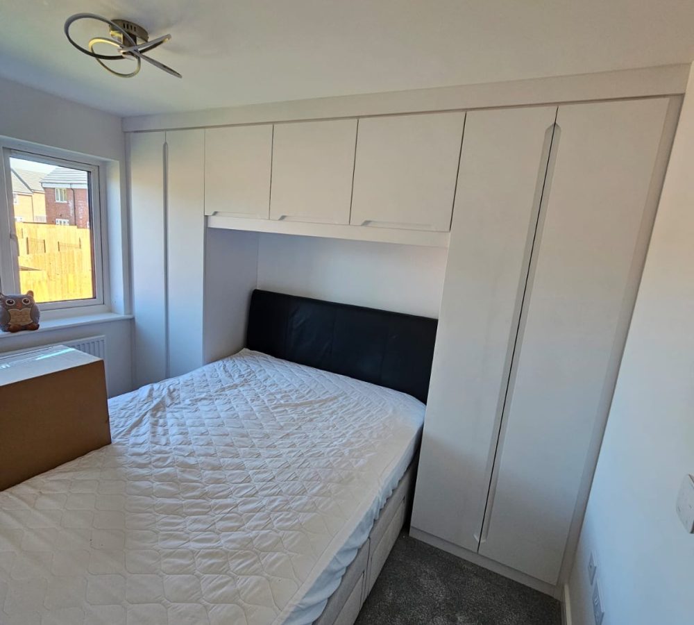 Bespoke over the bed White wardrobes with built in handles in the doors.