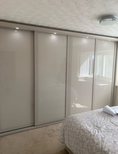 Fitted sliding door wardrobes in the colour Cashmere. There are four doors in the wardrobe and each door is fitted with Cashmere coloured glass.
