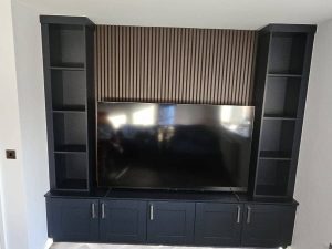 Made-to-measure media wall with Shaker low-unit cupboards, bookcase shelving and acoustic wall panelling. Finished in a combination of Walnut and Navy Blue.