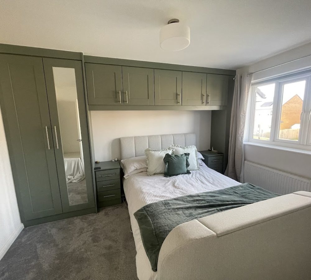 Over bed green cabinets and matching wardrobe with mirror panel